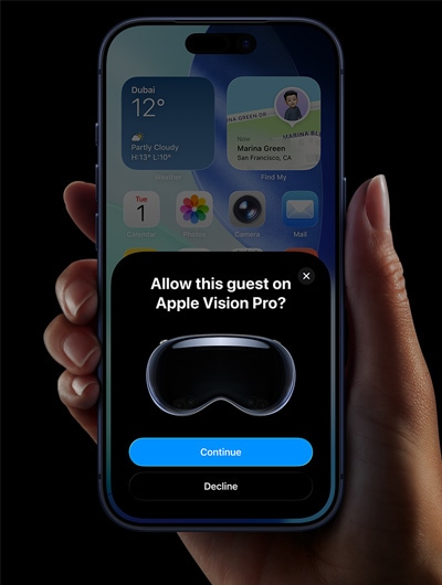 A hand holding an iPhone, the iPhone screen displays a window with the message: Allow this guest on Apple Vision Pro with buttons labeled: Continue and Decline