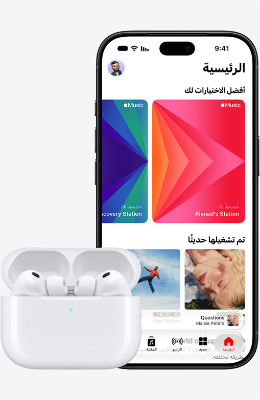 iPhone 18 Pro، الجهة الخارجية الأمامية، شاشة رئيسية لتطبيق Apple Music معروضة على الشاشة، بجانب سماعات Airpods Pro 3 في علبة شحن MagSafe مفتوحة