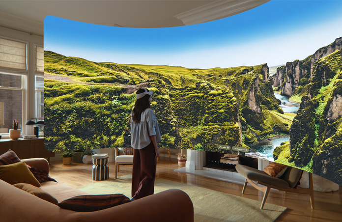 منظر من خلال Apple&nbsp;Vision&nbsp;Pro، صورة بانورامية لمنحدرات صخرية خضراء يتدفق بينها نهر وسماء زرقاء تمتد إلى ما بعد المنحدرات