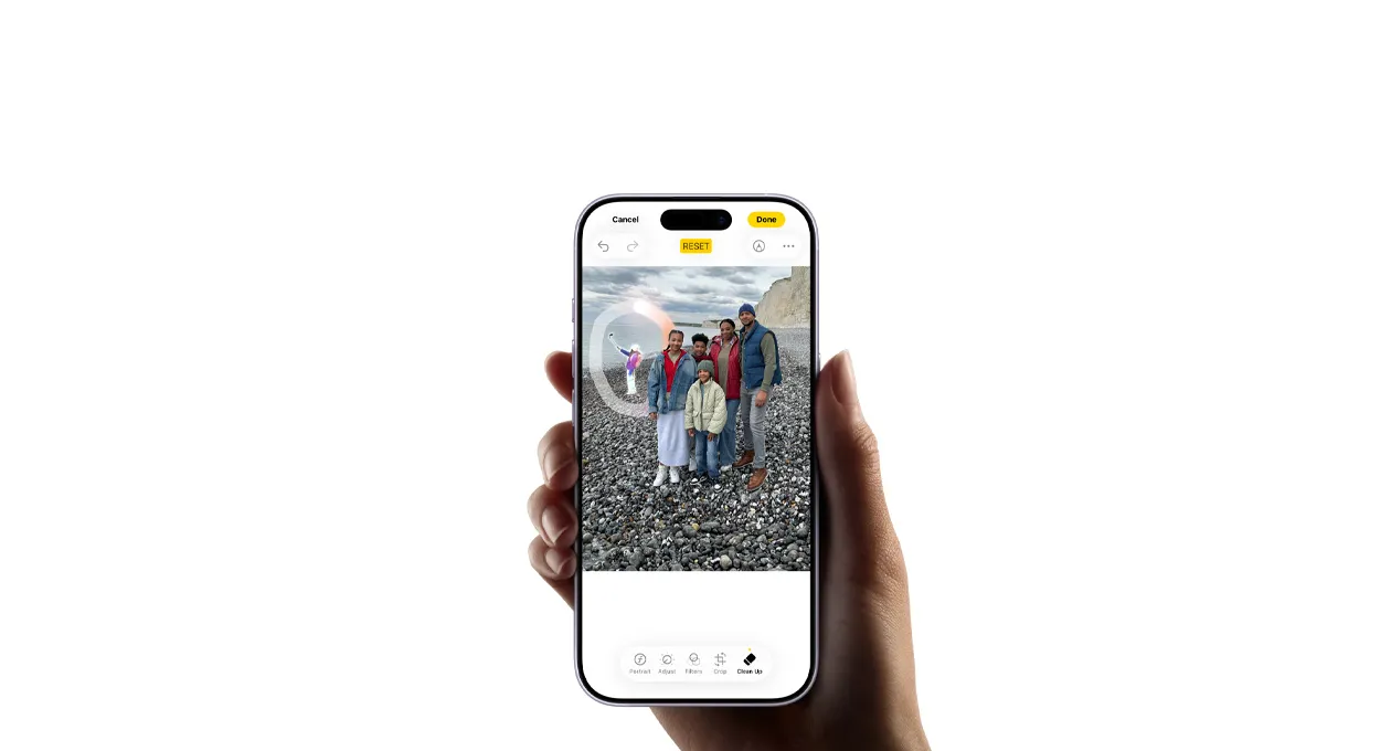 一隻手握著 iPhone 17，展示相機清除工具移除背景人物。