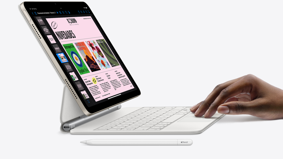 Imagen lateral de un iPad Air con la app Keynote en pantalla. El iPad Air está conectado a un Magic Keyboard, se muestra una mano apoyada sobre el trackpad y un Apple Pencil junto al teclado.