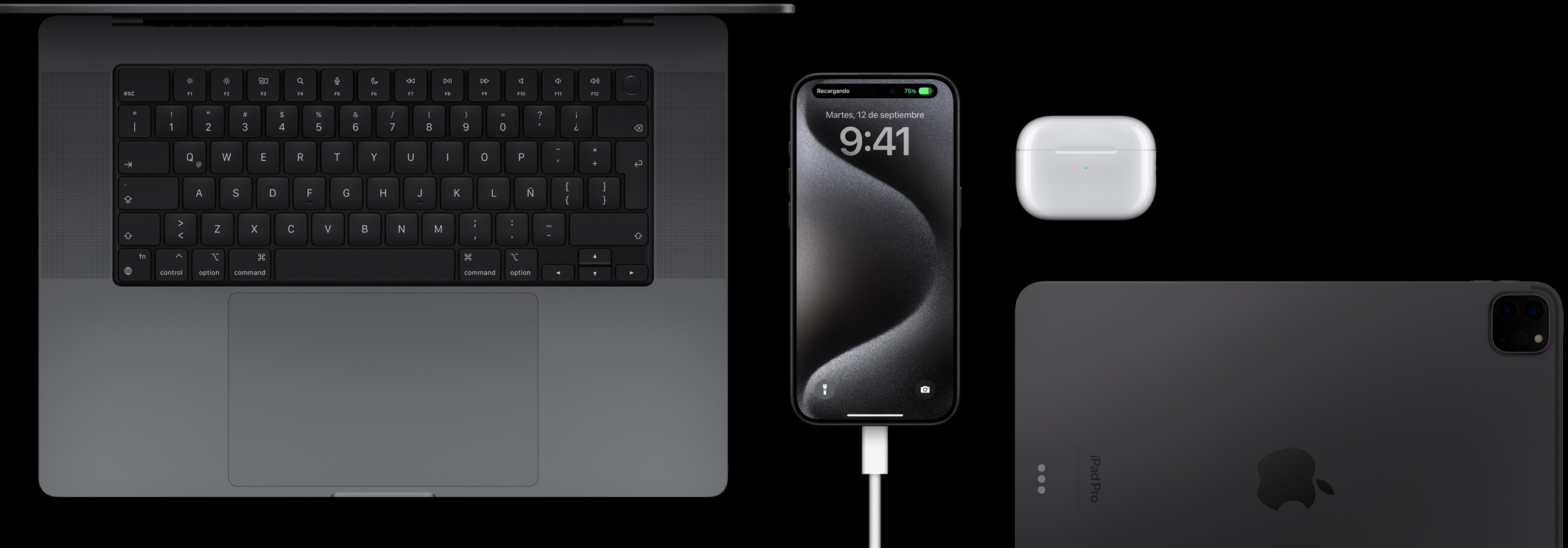 Un iPhone 15 Pro con un cable USB-C conectado, rodeado por una MacBook Pro, unos AirPods Pro y un iPad