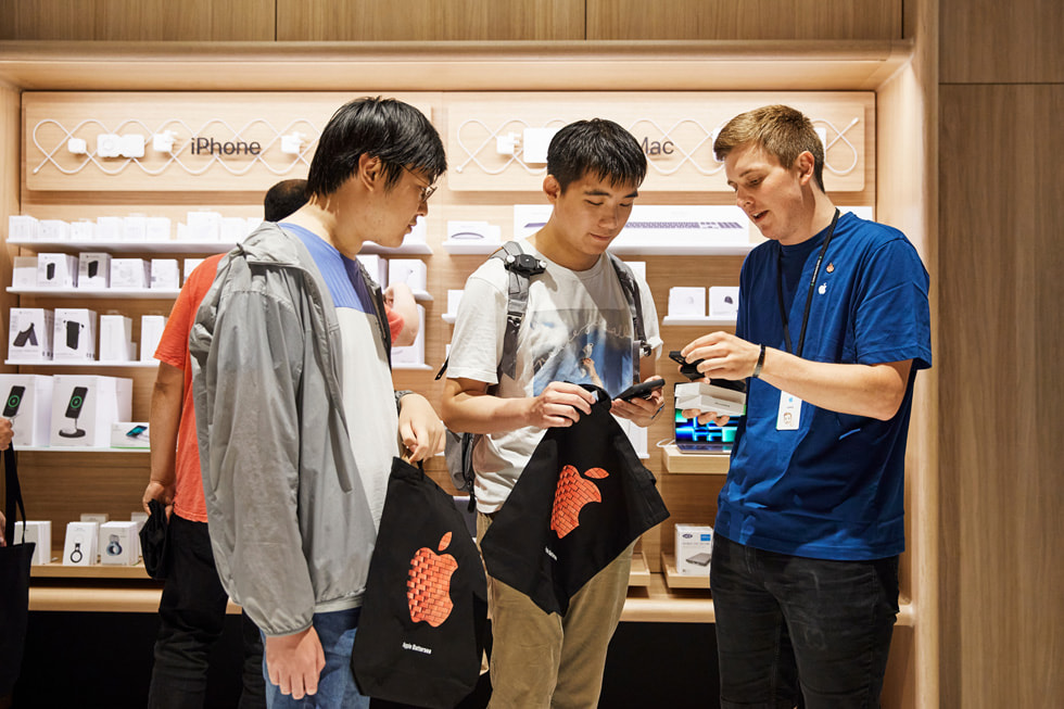 Un membre de l’équipe Apple aide des clients à découvrir iPhone 14 à la boutique Apple Battersea.