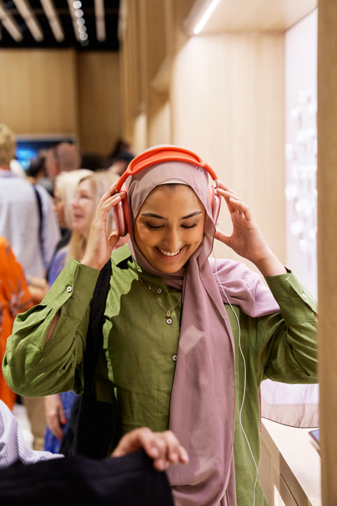 Une cliente essaie les AirPods Max à la boutique Apple Battersea.