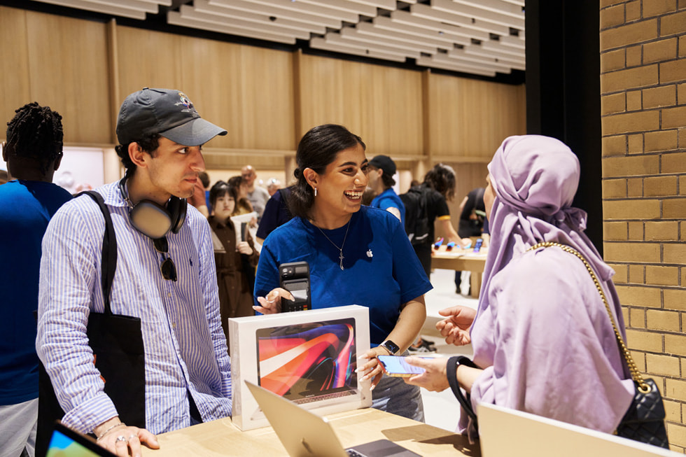 Ein Apple Teammitglied hilft einer Kundin beim Kauf ihres neuen MacBook Pro.
