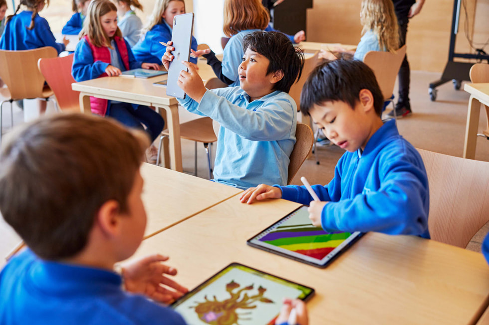 De jeunes élèves assis autour d’une table utilisent l’iPad Pro et l’Apple Pencil.