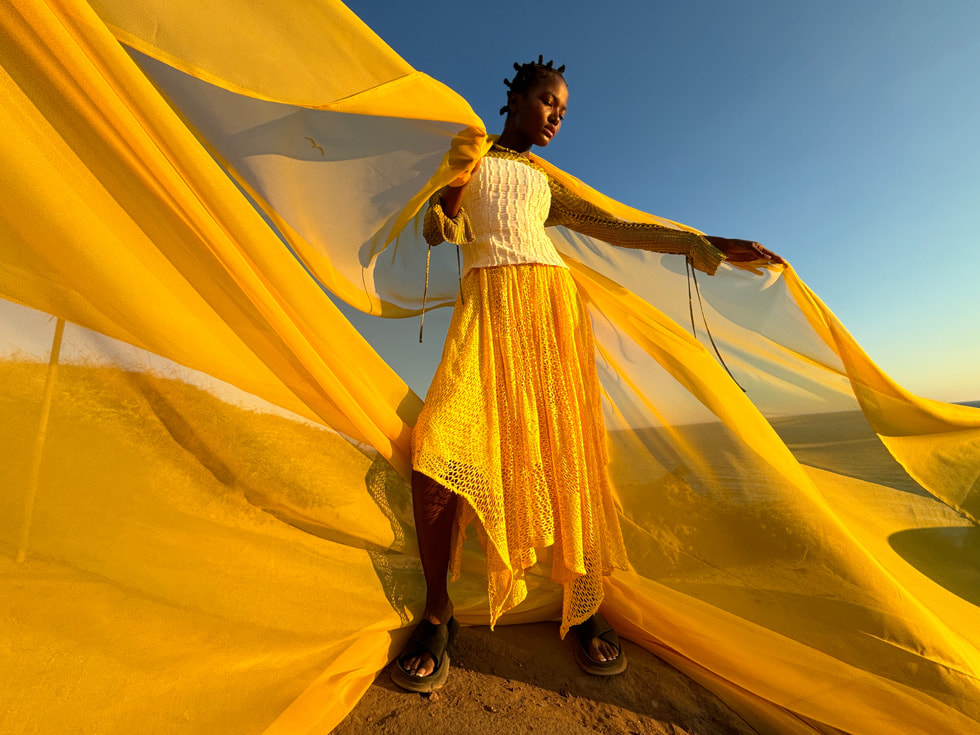 A photo taken on iPhone 15 shows a person wearing a yellow scarf that stretches across the frame.