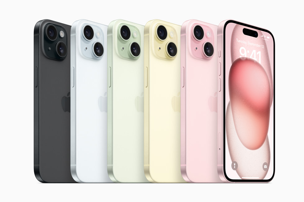 A row of iPhone 15 devices show the lineup’s new colours: black, blue, green, yellow, and pink.