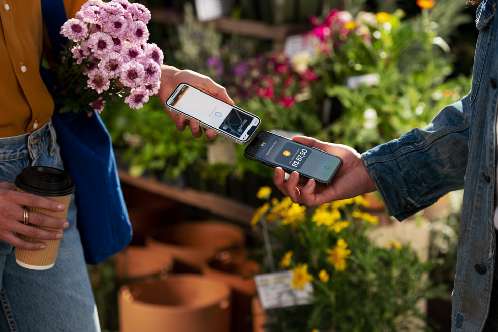 Uma cliente e um comerciante aproximam seus aparelhos iPhone para finalizar o pagamento.