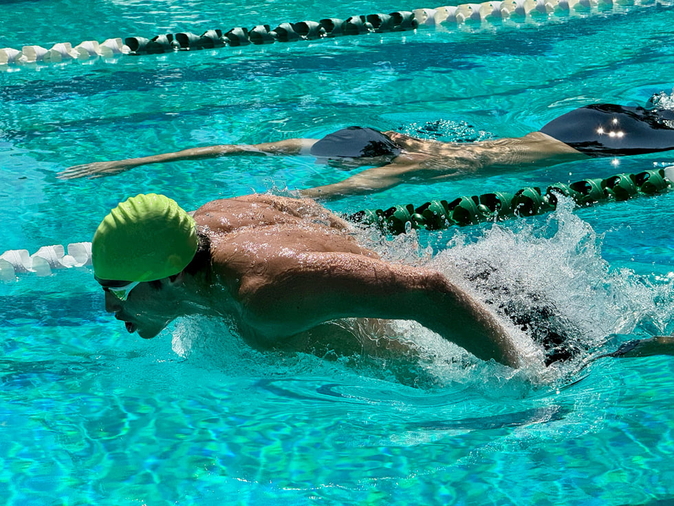 Eine schwimmende Person in einem Pool, aufgenommen mit der neuen 5-fach Tele-Zoom Kamera des iPhone 15 Pro Max.