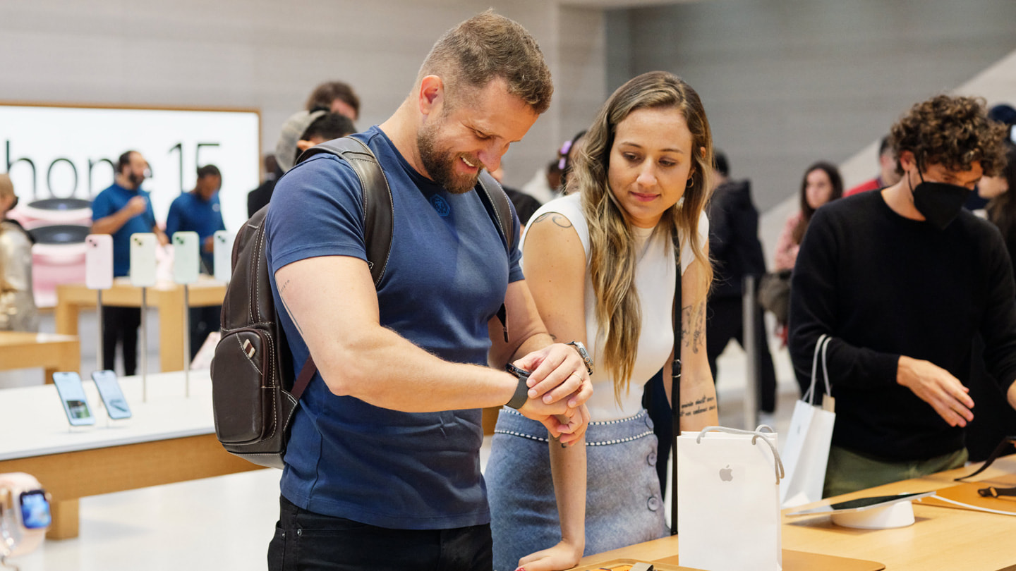 Two customers explore the latest Apple Watch lineup at Apple Fifth Avenue in New York City. The customer on the left tries on Apple Watch Series 9.