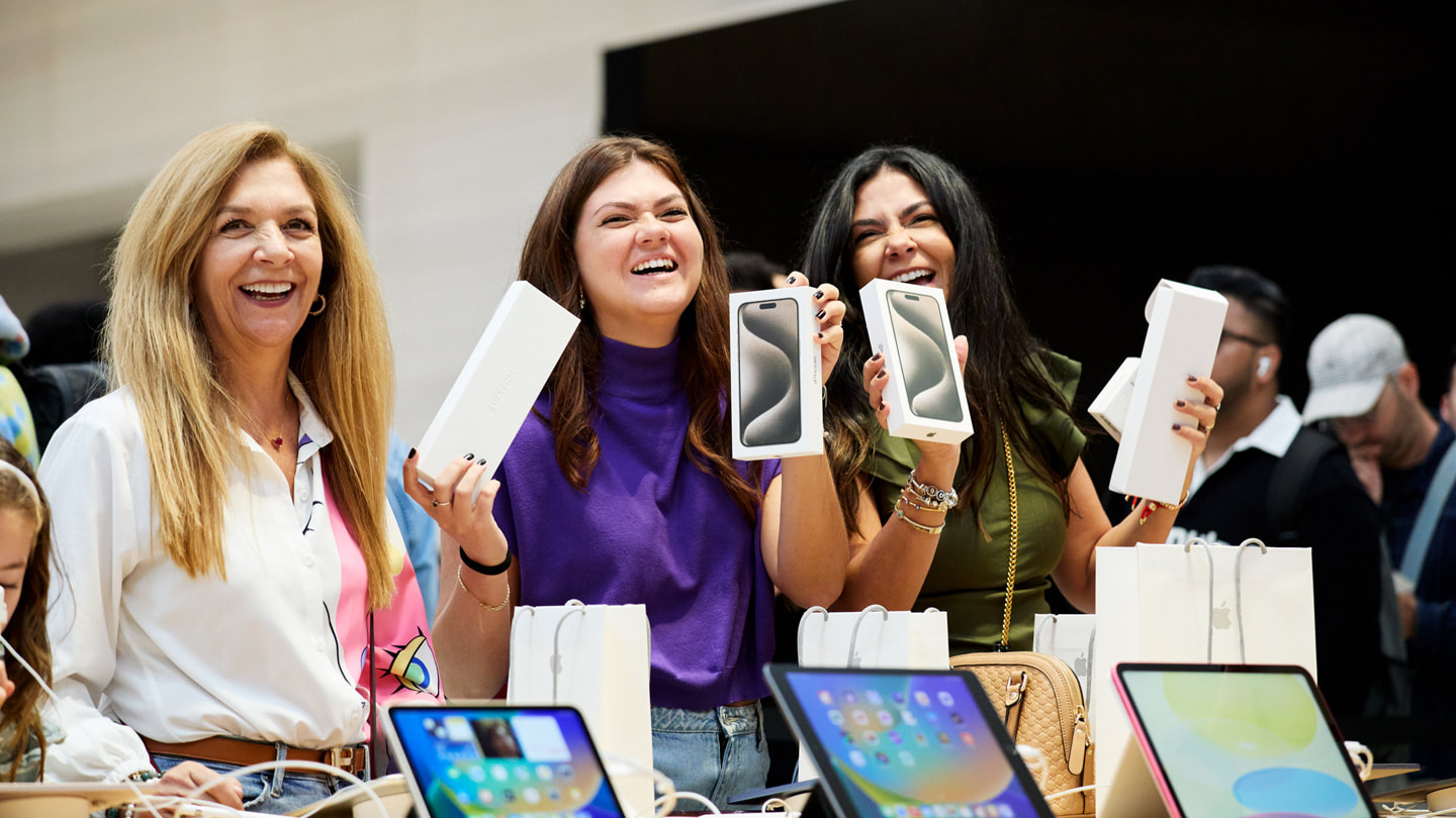 Clientes satisfeitas mostram suas compras da linha do iPhone 15 na Apple Fifth Avenue em Nova York.