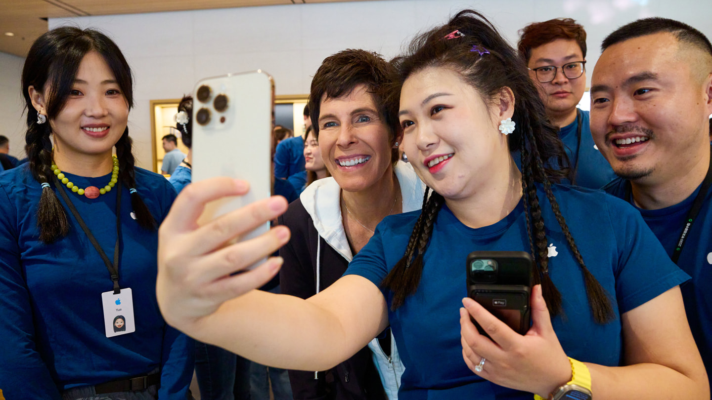 Zaměstnanec Applu si pořizuje selfie s Deirdrou O’Brien a dalšími na iPhone 15 Pro.