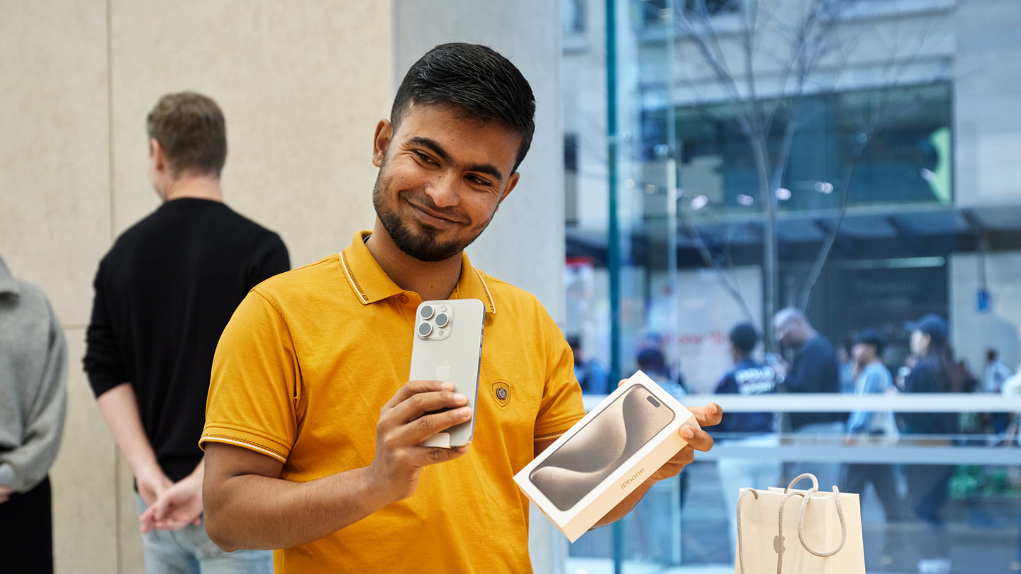 Zadowolony klient w sklepie Apple Sydney w Australii, który trzyma nowego iPhone’a 15 Pro.