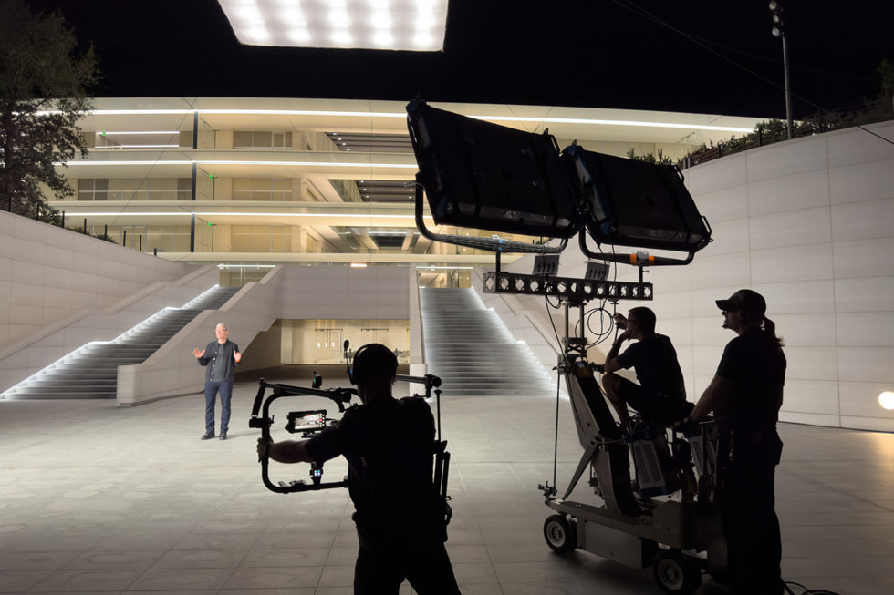 Mitglieder der Crew filmen Tim Cook vor der Außentreppe im Apple Park.