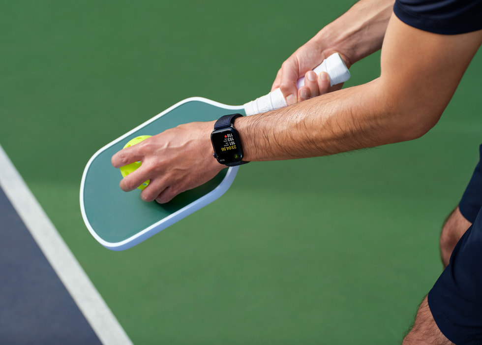 A pickleball racket and ball held by a player are shown.