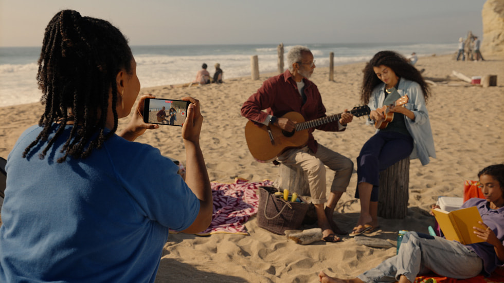 Iemand neemt op het strand een ruimtelijke video op met een iPhone 15 Pro.