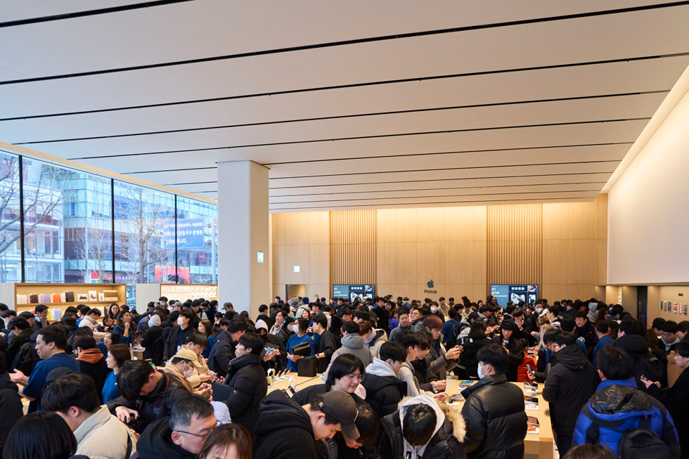 A atmosfera fervilhante dentro da Apple Hongdae, onde dezenas de clientes exploram a loja.