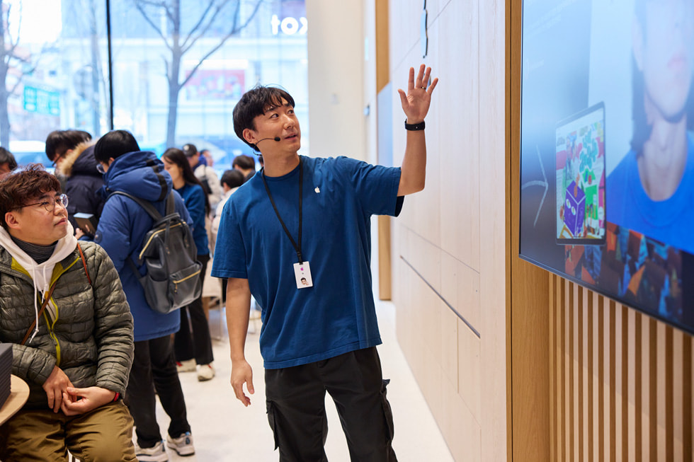 ทีมงานคนหนึ่งกำลังแนะนำเซสชั่น Apple Pop-Up Studio จากศิลปิน Beenzino กับลูกค้า