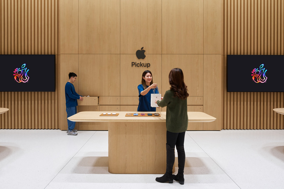 A customer speaks with a team member at the store's dedicated Apple Pickup area.