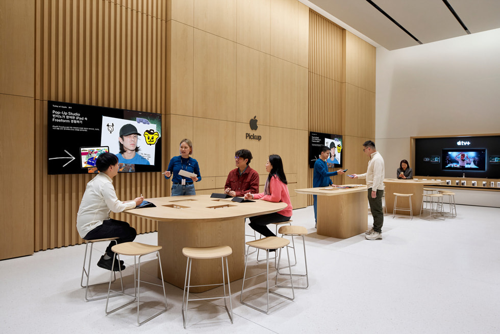 Customers sit at a Today at Apple table inside the store.
