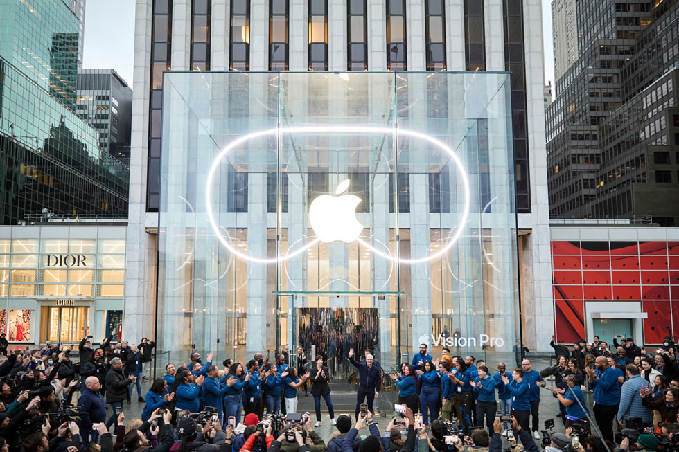 Tim Cook and Deirdre O'Brien outside Apple Fifth Avenue with team members and a crowd of customers. 