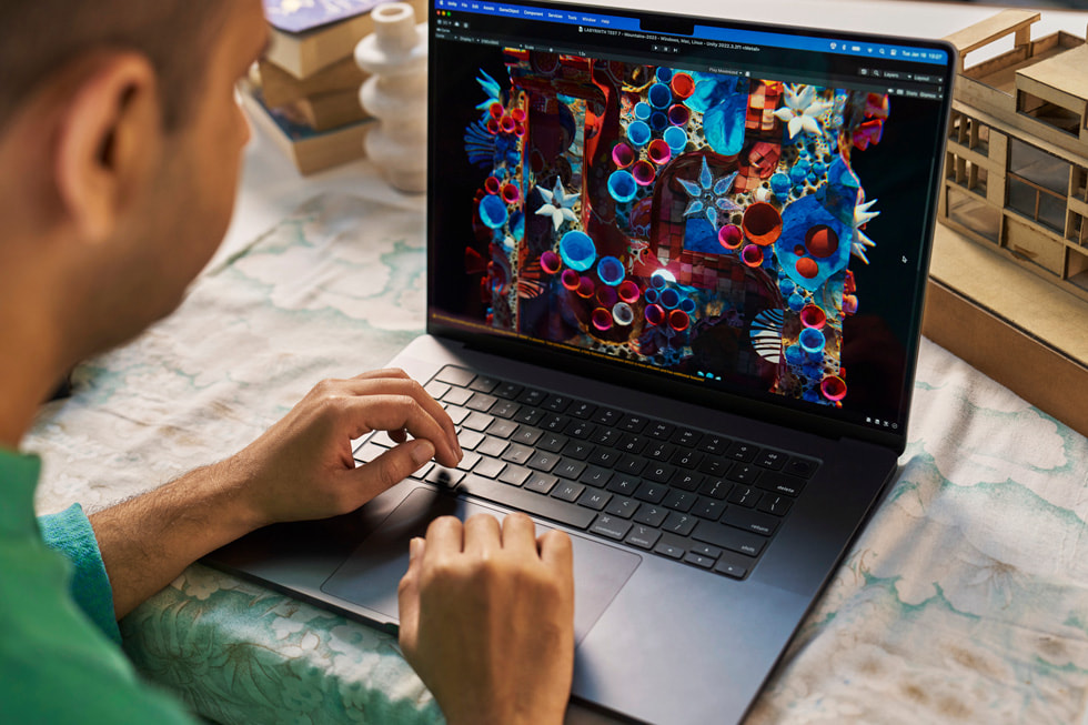 Dhruv Jani using MacBook Pro, which displays colourful shapes.