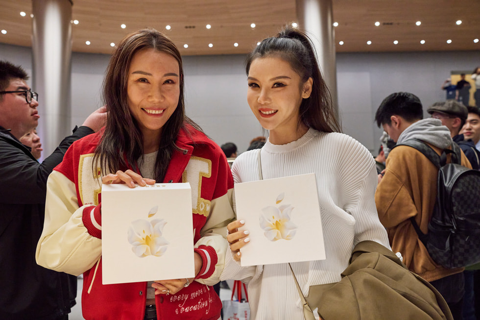 Des clientes montrent des articles promotionnels de l’inauguration d’Apple Jing’an.