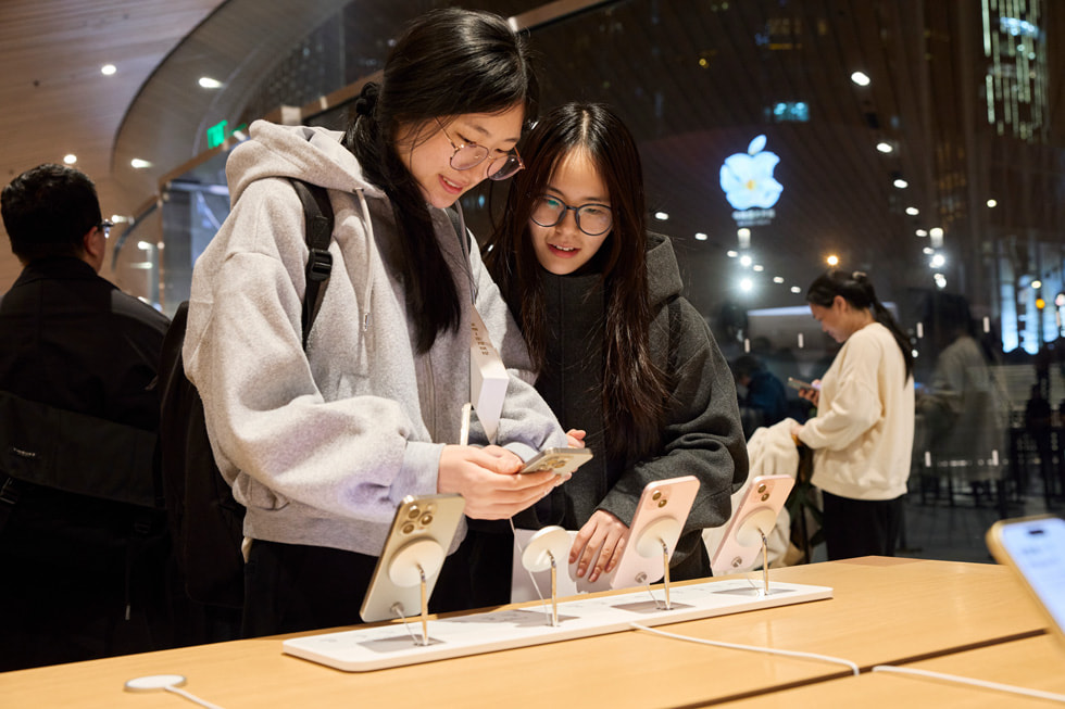 ลูกค้าที่ Apple Jing’an ยืนอยู่ใกล้กับโต๊ะจัดแสดง iPhone 15 รุ่นต่างๆ