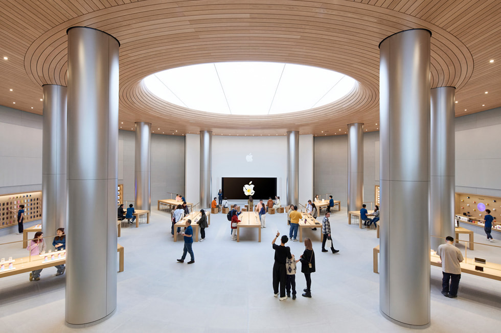 Hình ảnh khách hàng đang chiêm ngưỡng sản phẩm Apple và dạo quanh khu vực Forum bên trong cửa hàng. 