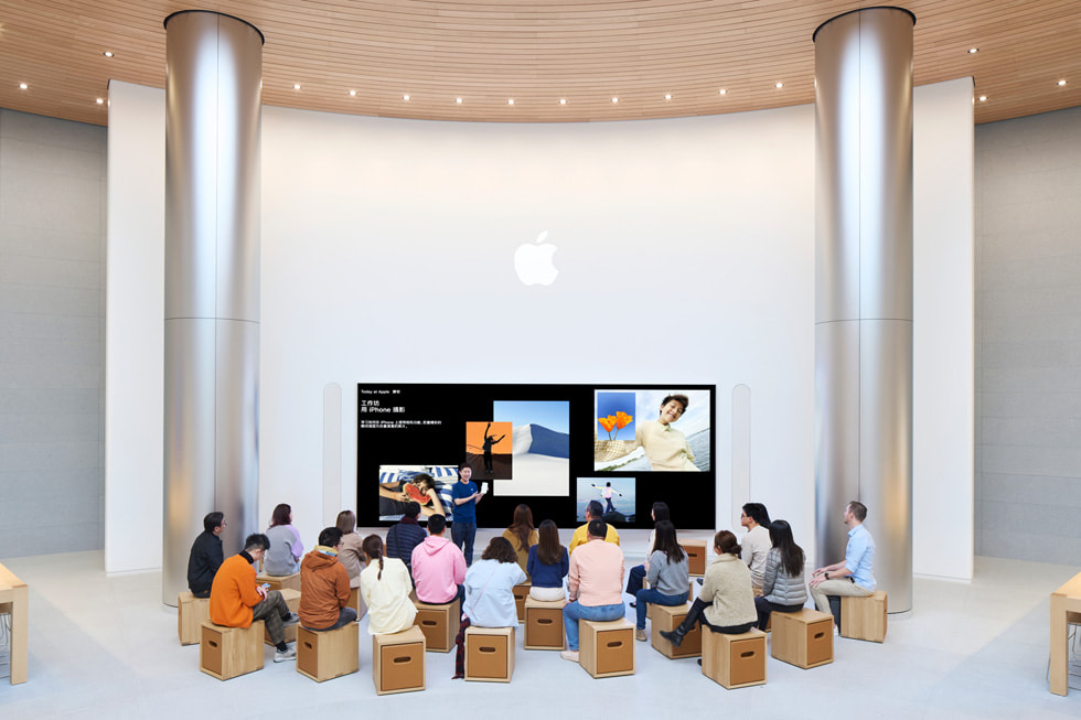 Clientes sentados frente a una pantalla gigante durante una sesión de Today at Apple.