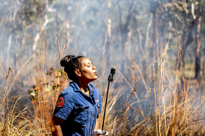 Josephine Austral apaga la antorcha de goteo tras realizar una quema de suelo en la zona de gestión de tierras  de Mimal Land.