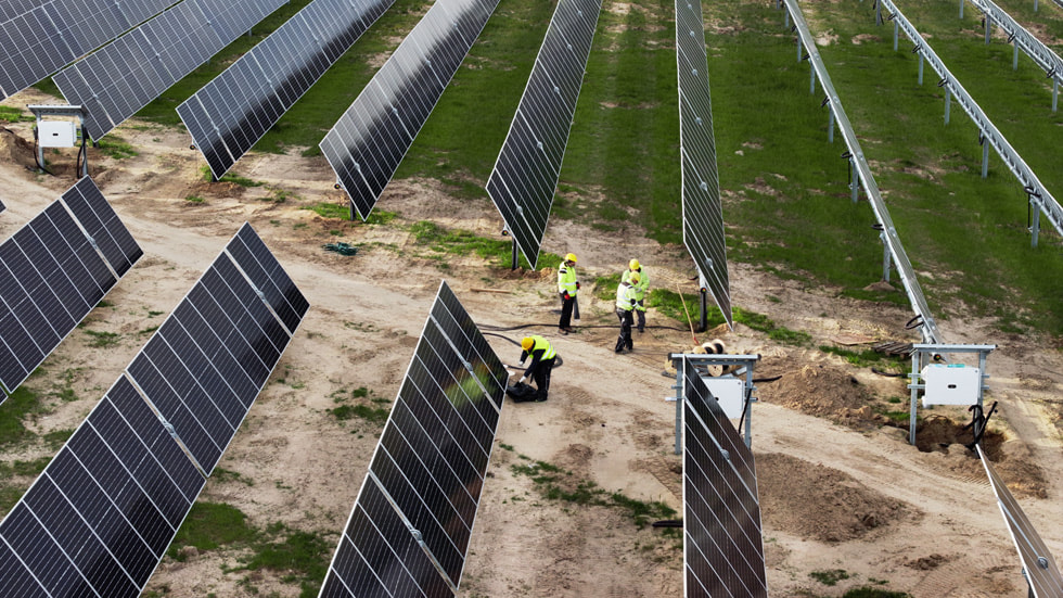 Solar panels and workers are shown in a field.