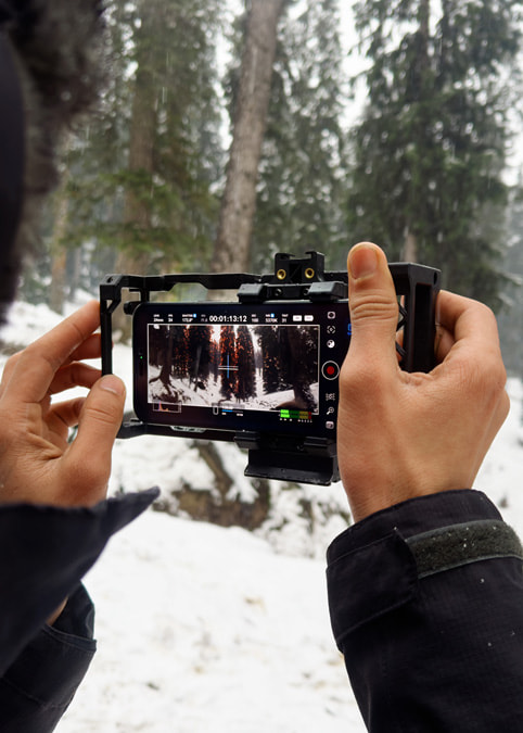 The hands of cinematographer Anand Bansal are shown holding iPhone 15 Pro Max in a pro rig by Beastgrip on the set of "Óbur."
