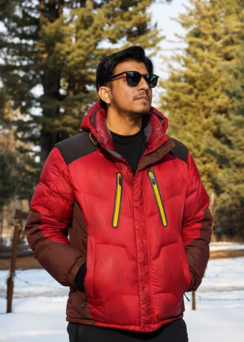 Filmmaker Faraz Ali stands in a snowy forest landscape.