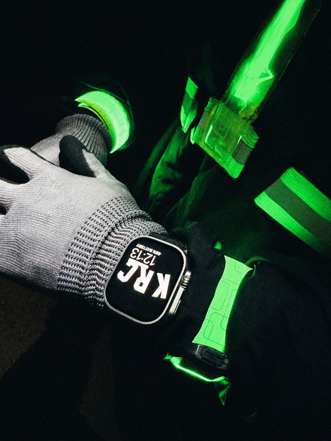 Et nærbillede af en løbers håndled, der viser Apple Watch Ultra om natten.
