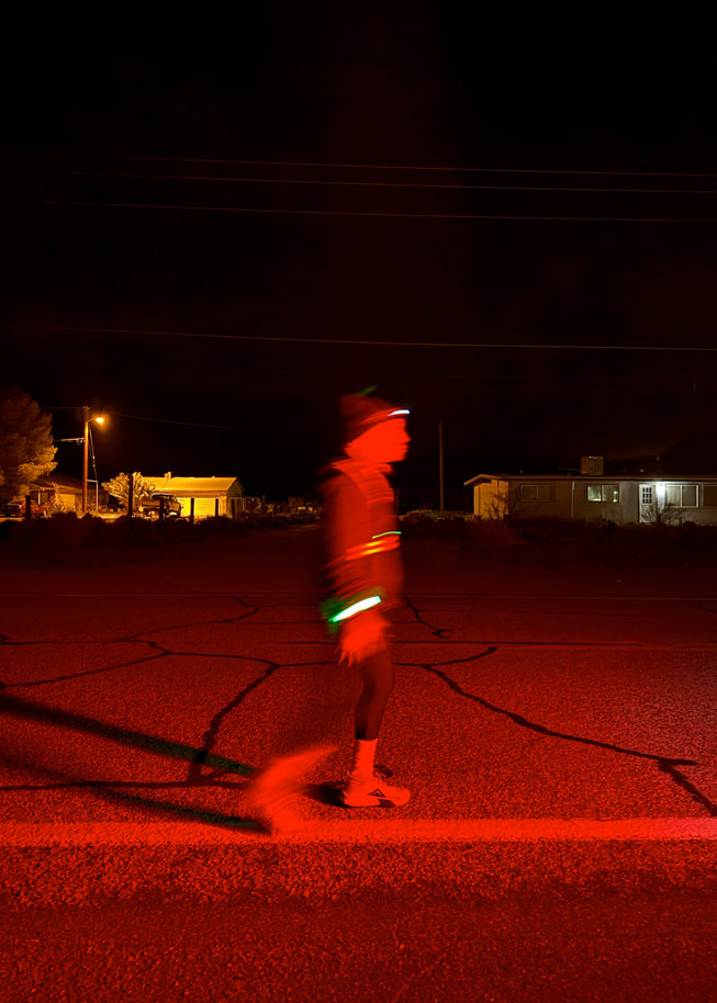 Cliché d’une personne équipée de vêtements réfléchissants courant dans l’obscurité sur la route.