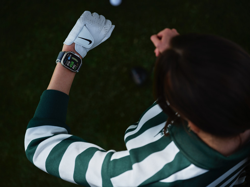 Zdjęcie z góry przedstawiające osobę grającą w golfa, która spogląda na swój Apple Watch.