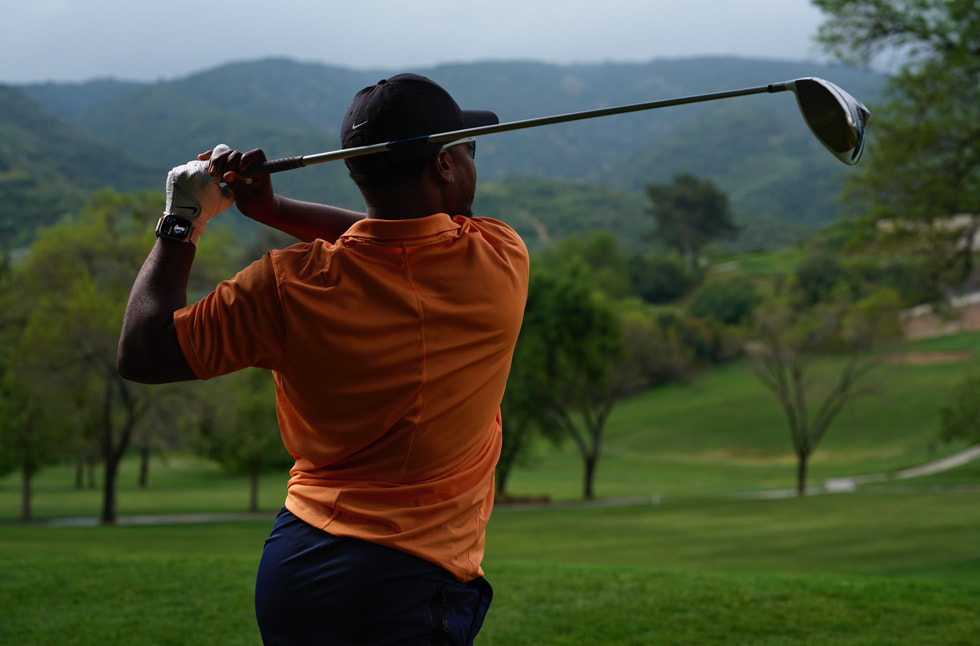 Foto seorang pegolf yang memakai Apple Watch sedang mengayunkan stik golf.