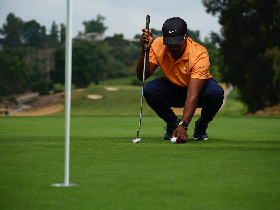 A golfer wearing Apple Watch while setting up a putt is shown.