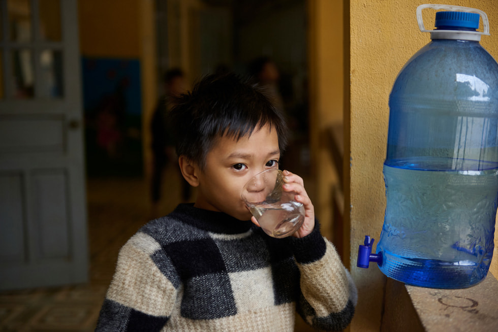 Zdjęcie ucznia pijącego wodę z instalacji Gravity Water w zespole szkół Vay Nua – szkole podstawowej i średniej z internatem przeznaczonej dla uczniów z mniejszości etnicznych. 