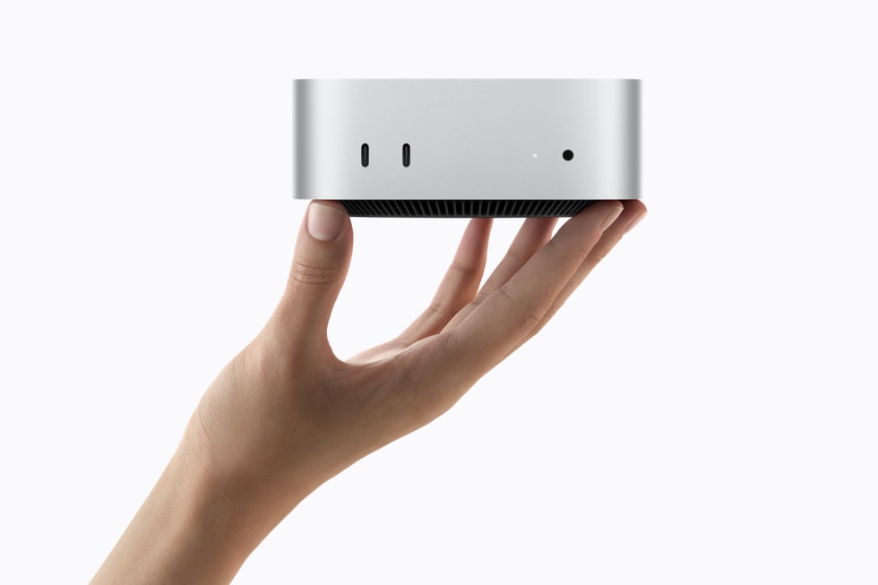 Eine Hand hält den Mac mini in Silber und zeigt seine Anschlüsse an der Vorderseite.