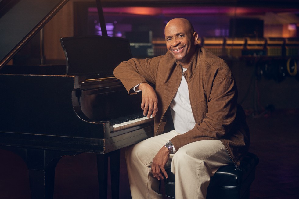 Sergio George ngồi bên đàn piano.