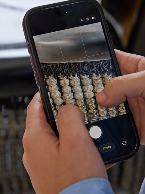 Two hands hold iPhone 18 Pro, which displays a close-up photo of the beaded fringe on 