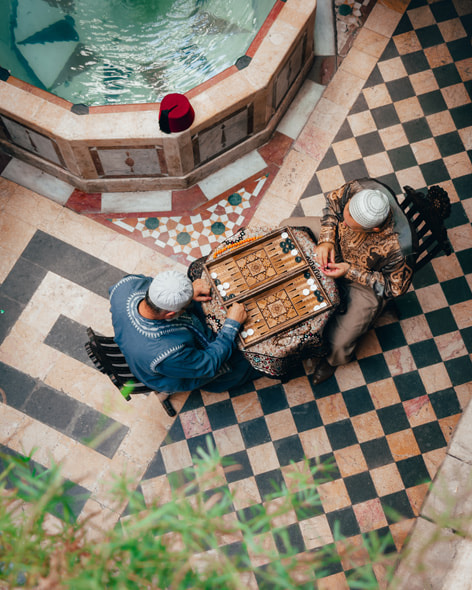 Two elderly Syrian men play a traditional Syrian board game in an ornate courtyard in Damascus.