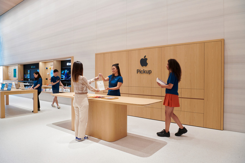ทีมงาน Apple ยื่นถุงให้ลูกค้า ณ จุดรับสินค้าที่ Apple ภายใน Apple Brompton Road