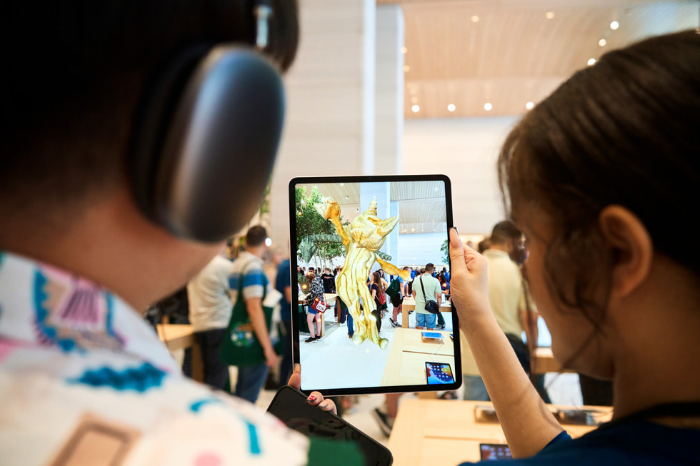 在 Apple Brompton Road 內，一名團隊成員協助顧客在 iPad Pro 上探索《United Visions》擴增實境體驗。