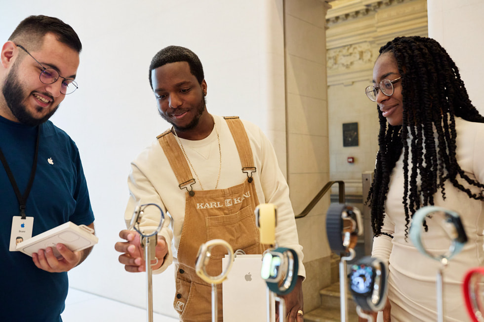 A customer standing outside of Apple Champs-Élysées looks at a window display featuring different iPhone devices.