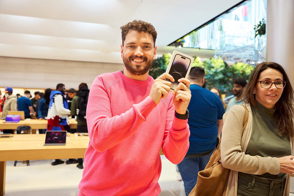 Een klant poseert enthousiast met de nieuwe iPhone 14 Pro. 