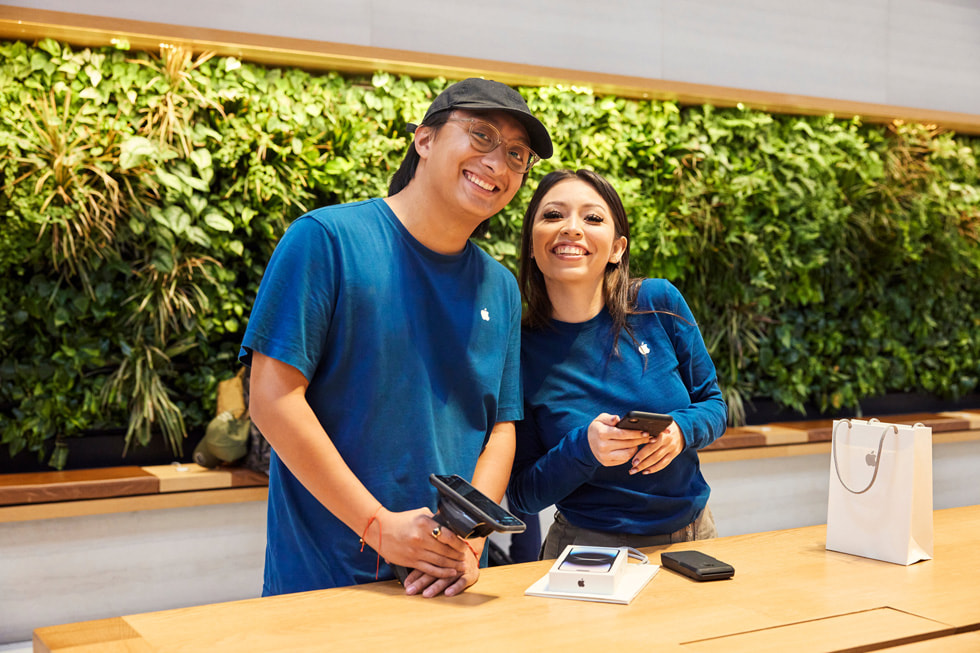 To Apple Fifth Avenue-teammedlemmer som hjelper en kunde. 